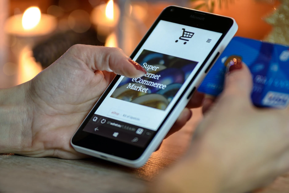 Woman holding a phone and credit card while doing the checkout from a webshop