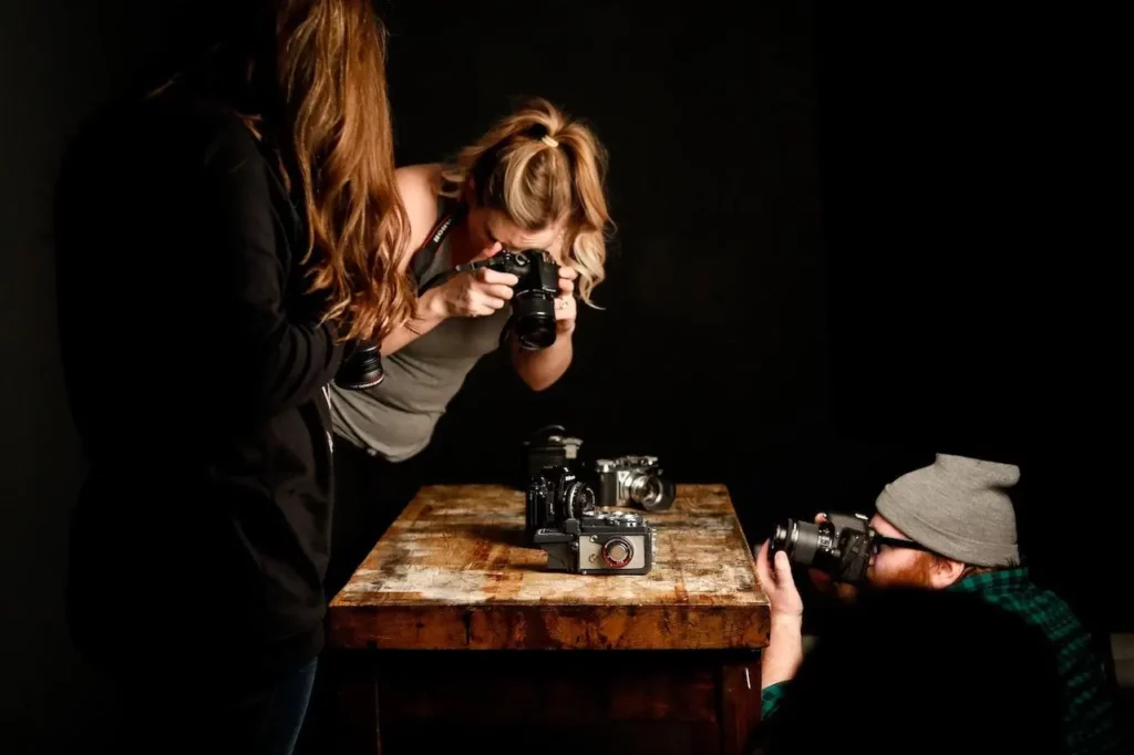 3 people are taking photos with cameras.